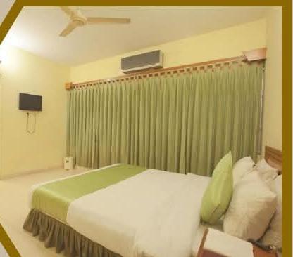 Comfortable Guest Room at Bashati Bay Resort Air-conditioned hotel room with a green curtain, ceiling fan, and wall-mounted TV.