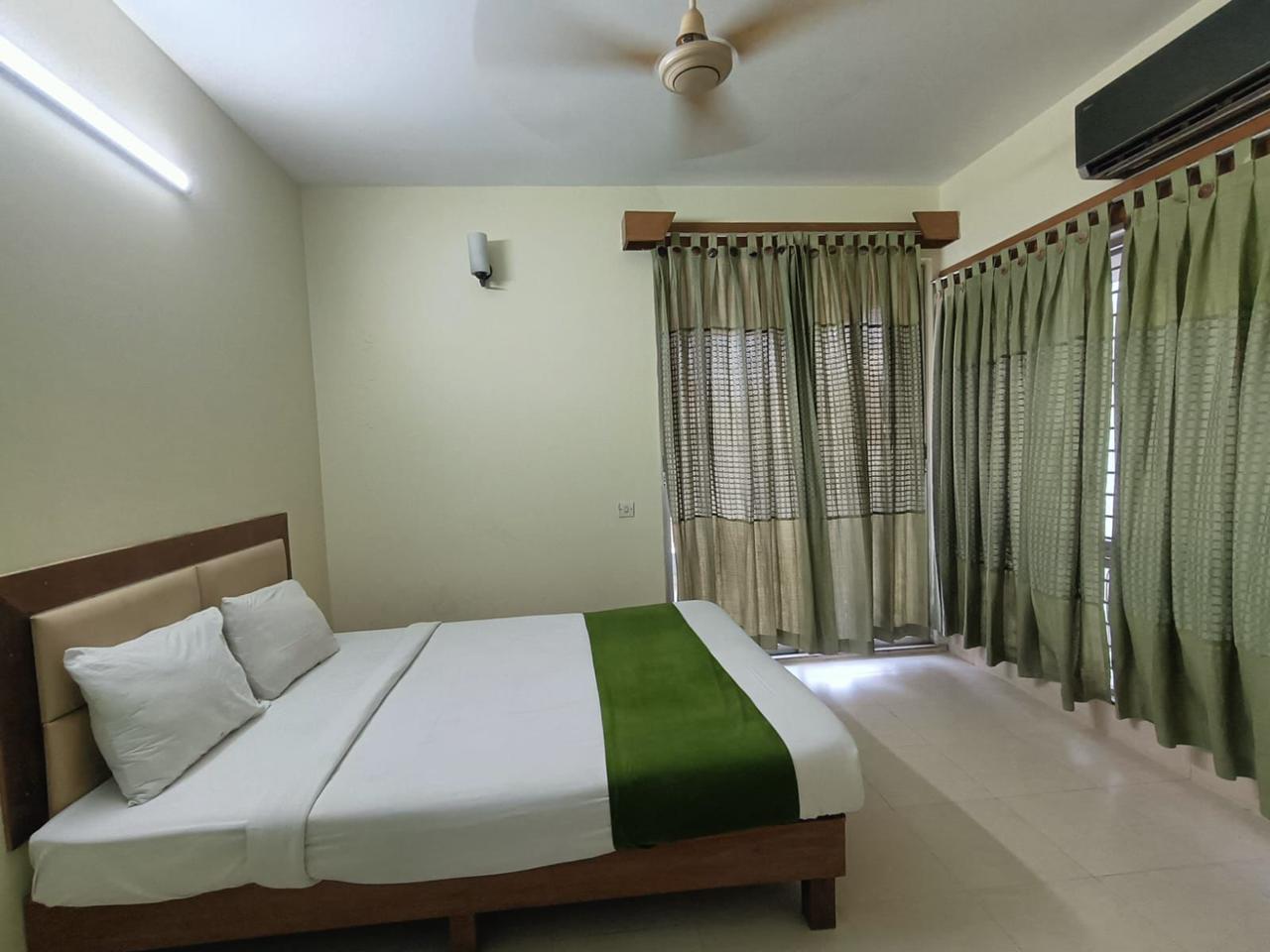 Corner Room with Natural Lighting Double bed hotel room with green curtains and bright natural light.